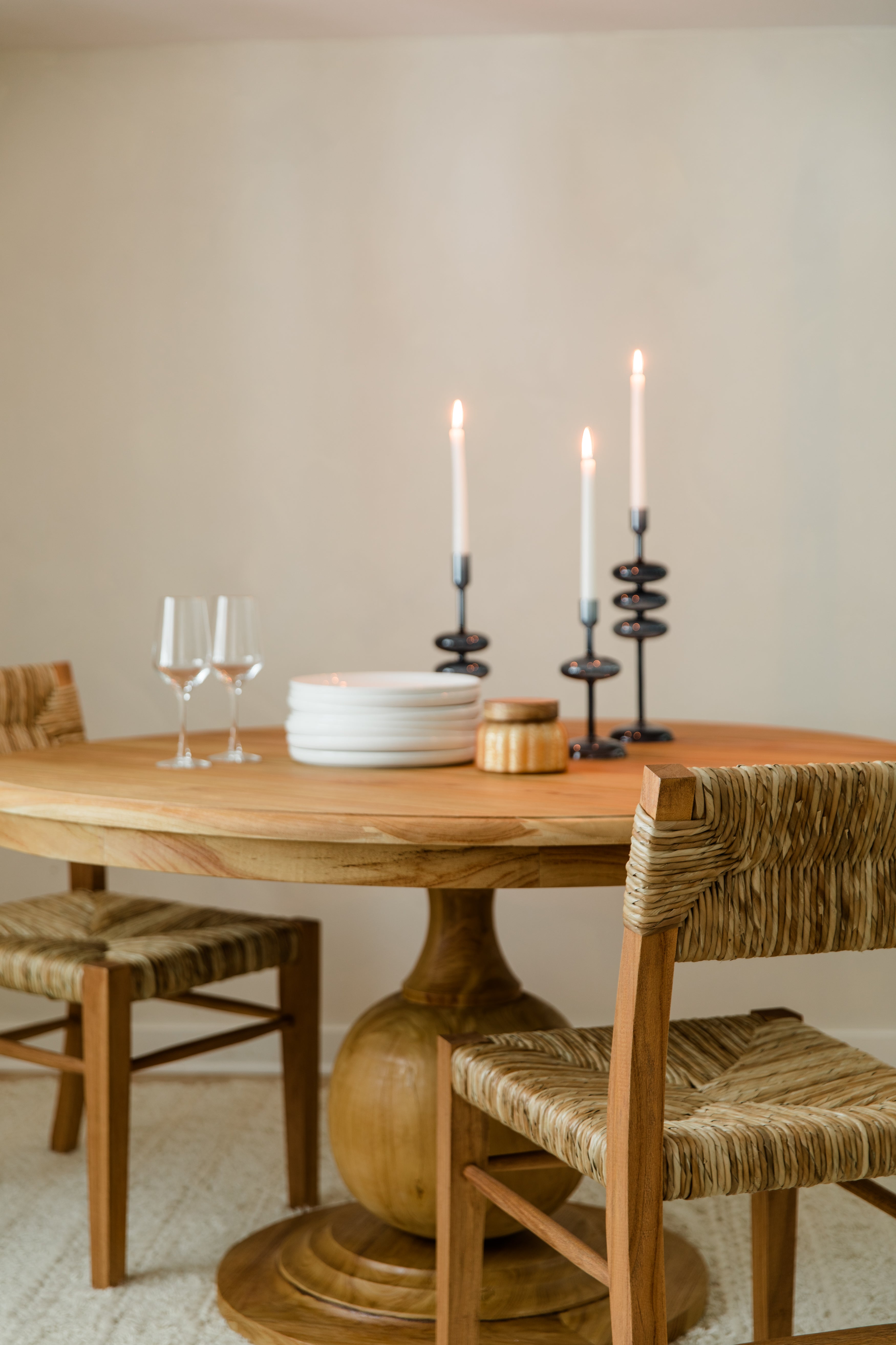 Cozy dining room scene with a natural round wooden table and seagrass and teak wood dining chairs