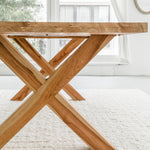 side profile of an elegant yet rustic teak dining table in solid wood with cross legs, including views of the natural wood grain