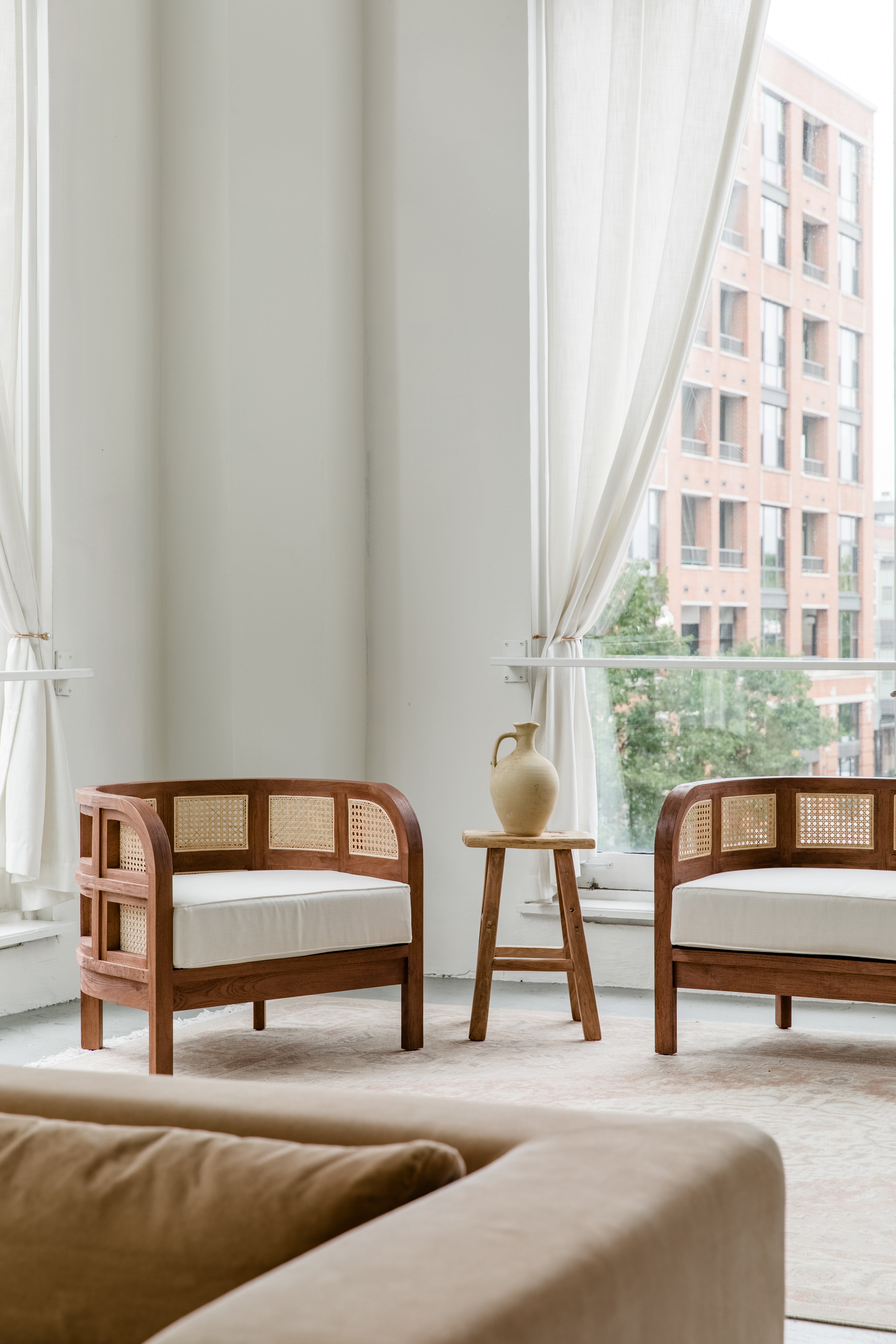 Living room scene with a pair of wooden walnut caned accent chairs with a natural vibe