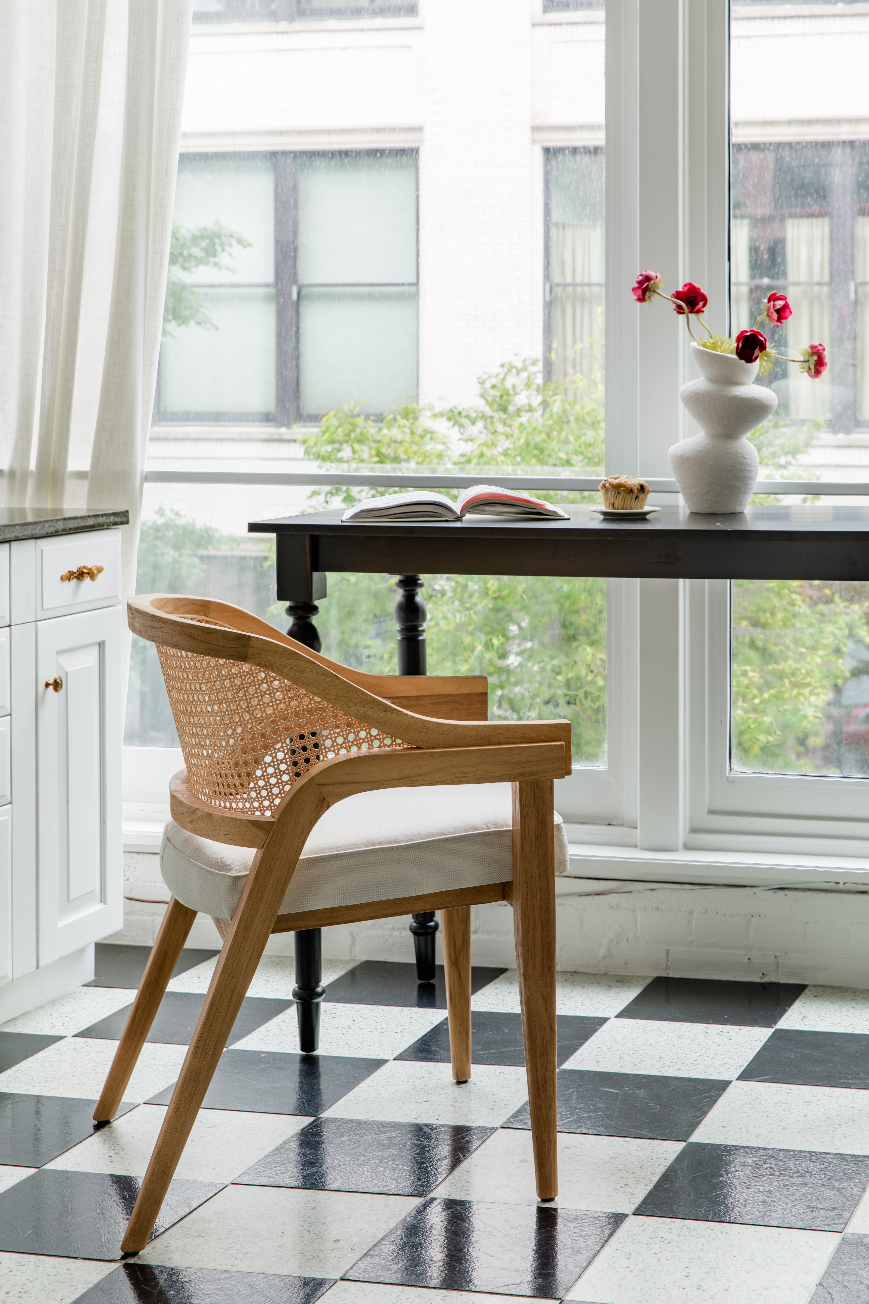 Parisian style kitchen with a checkerboard floor and a natural wooden caned curved back chair
