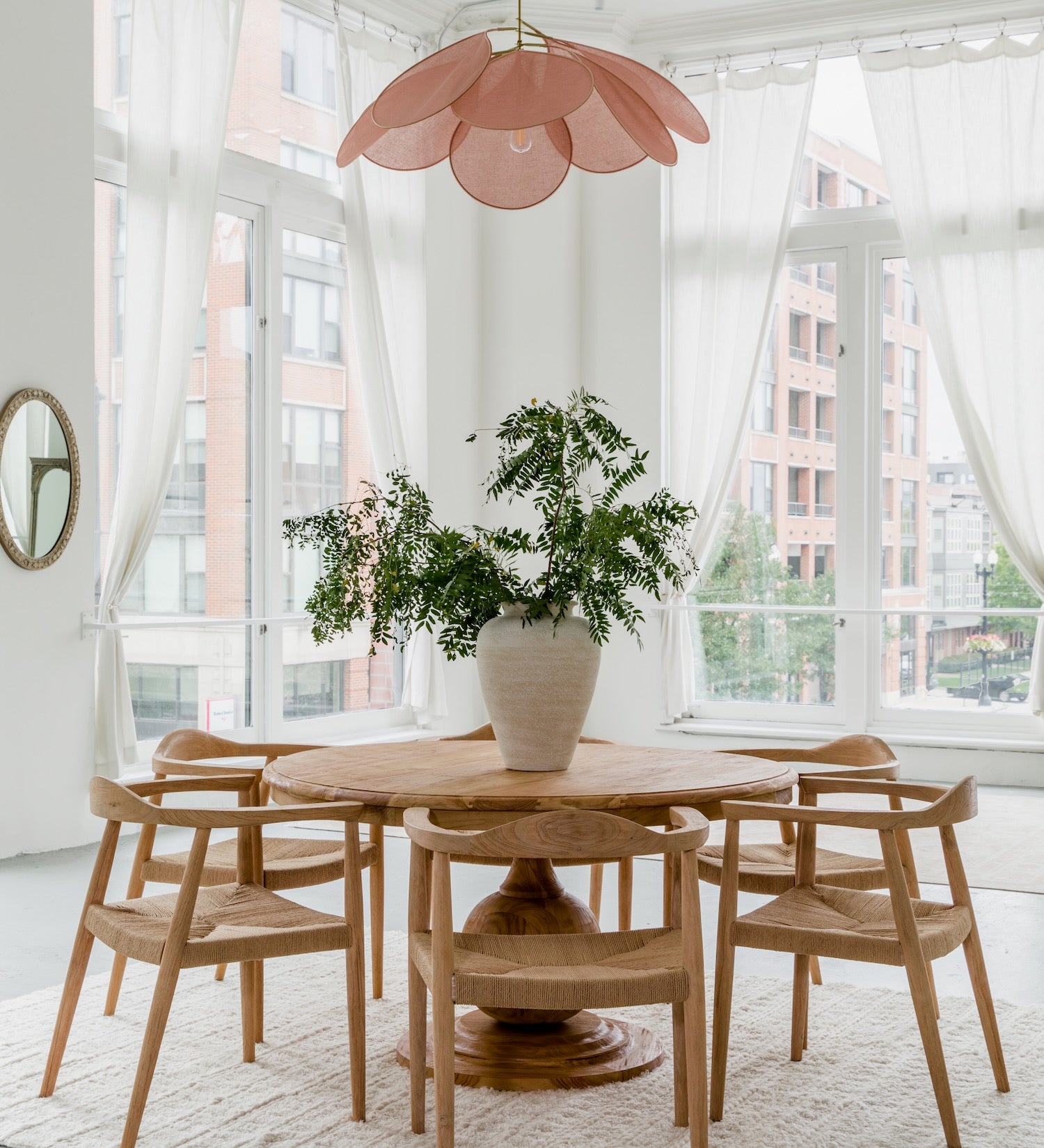 natural round dining table with dining chairs in a parisian style high ceiling dining room