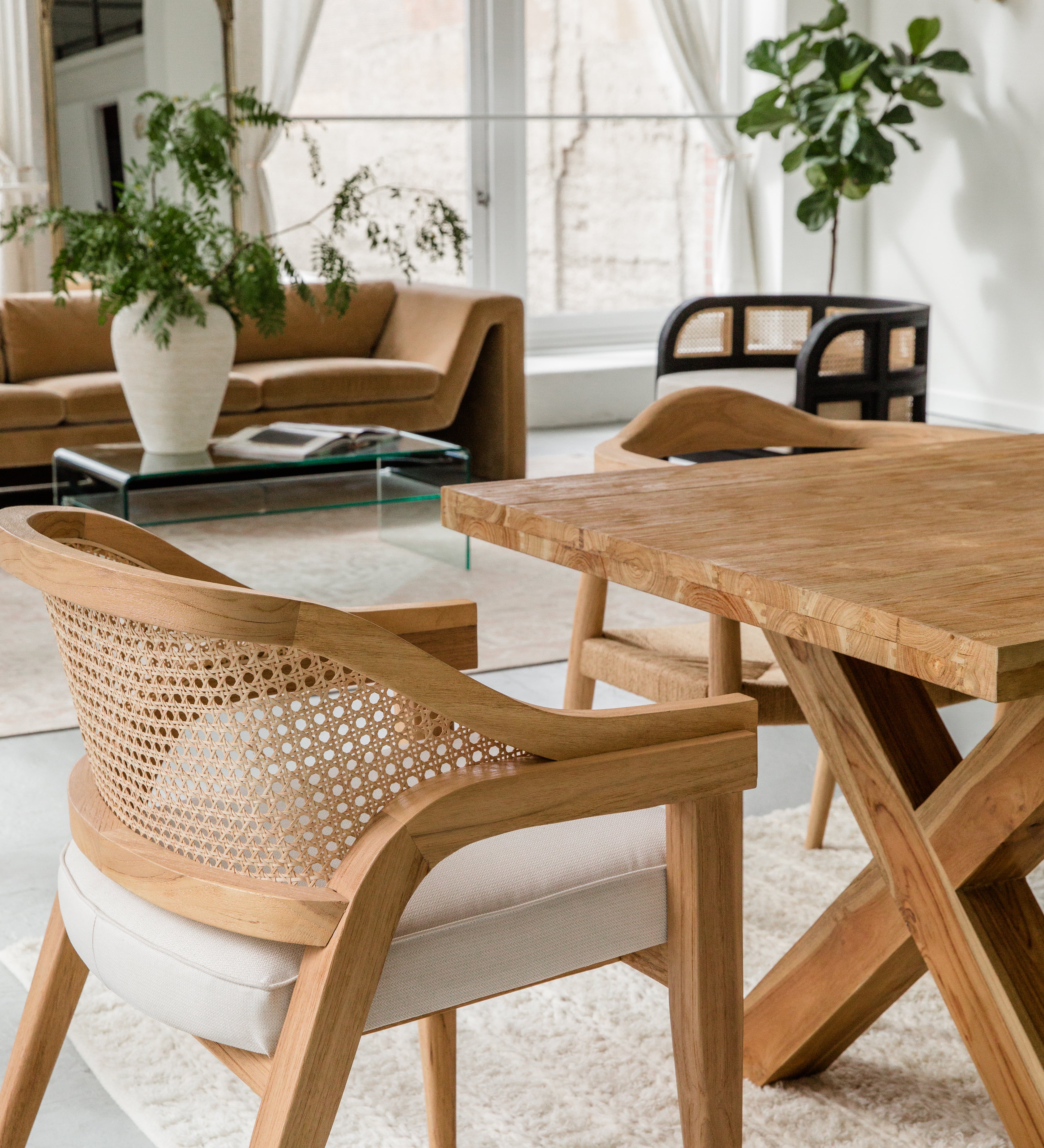 open concept dining room and living room scene zoomed in on a natural wooden caned chair with a curved back