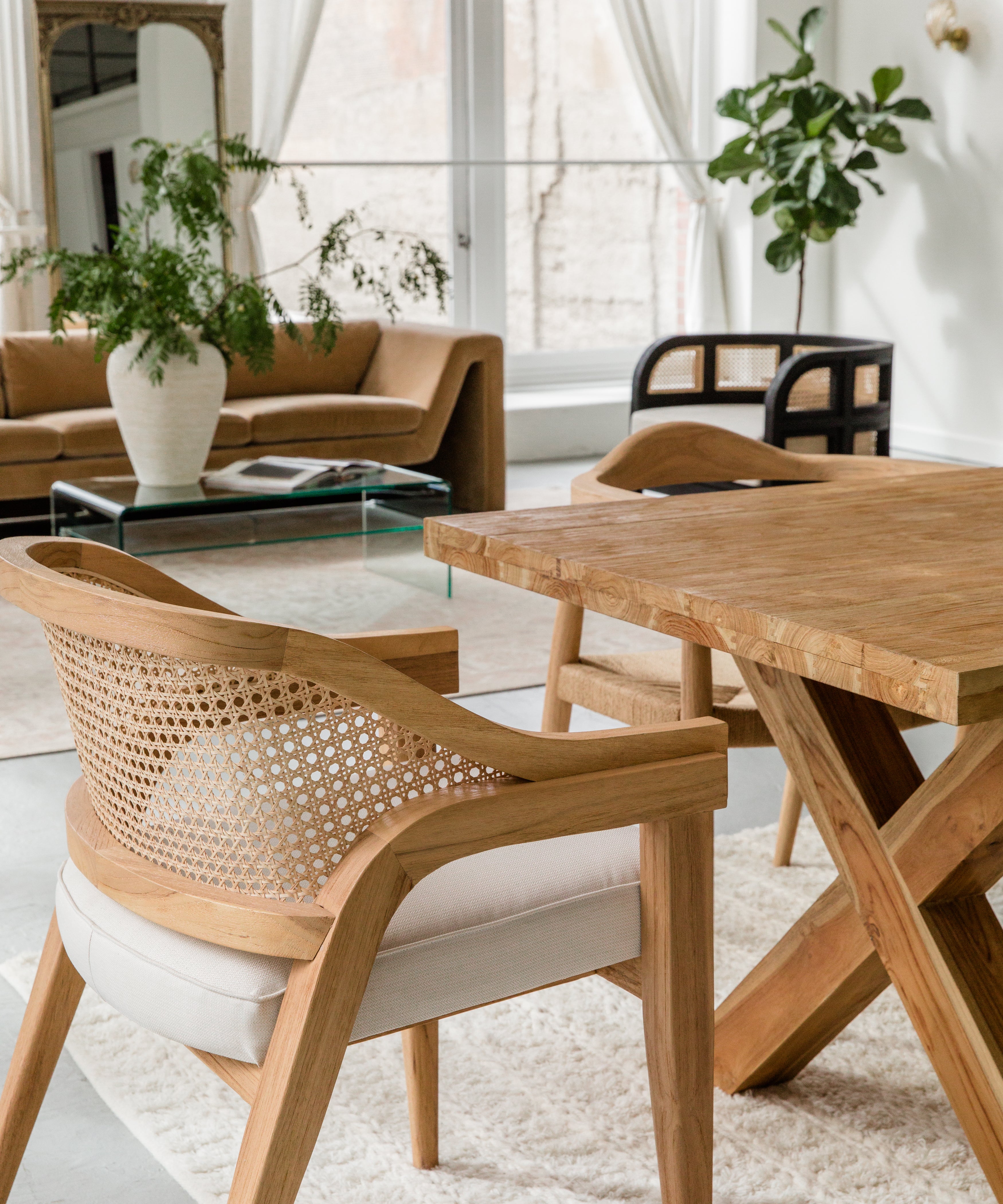 open concept dining room and living room scene zoomed in on a natural wooden caned chair with a curved back