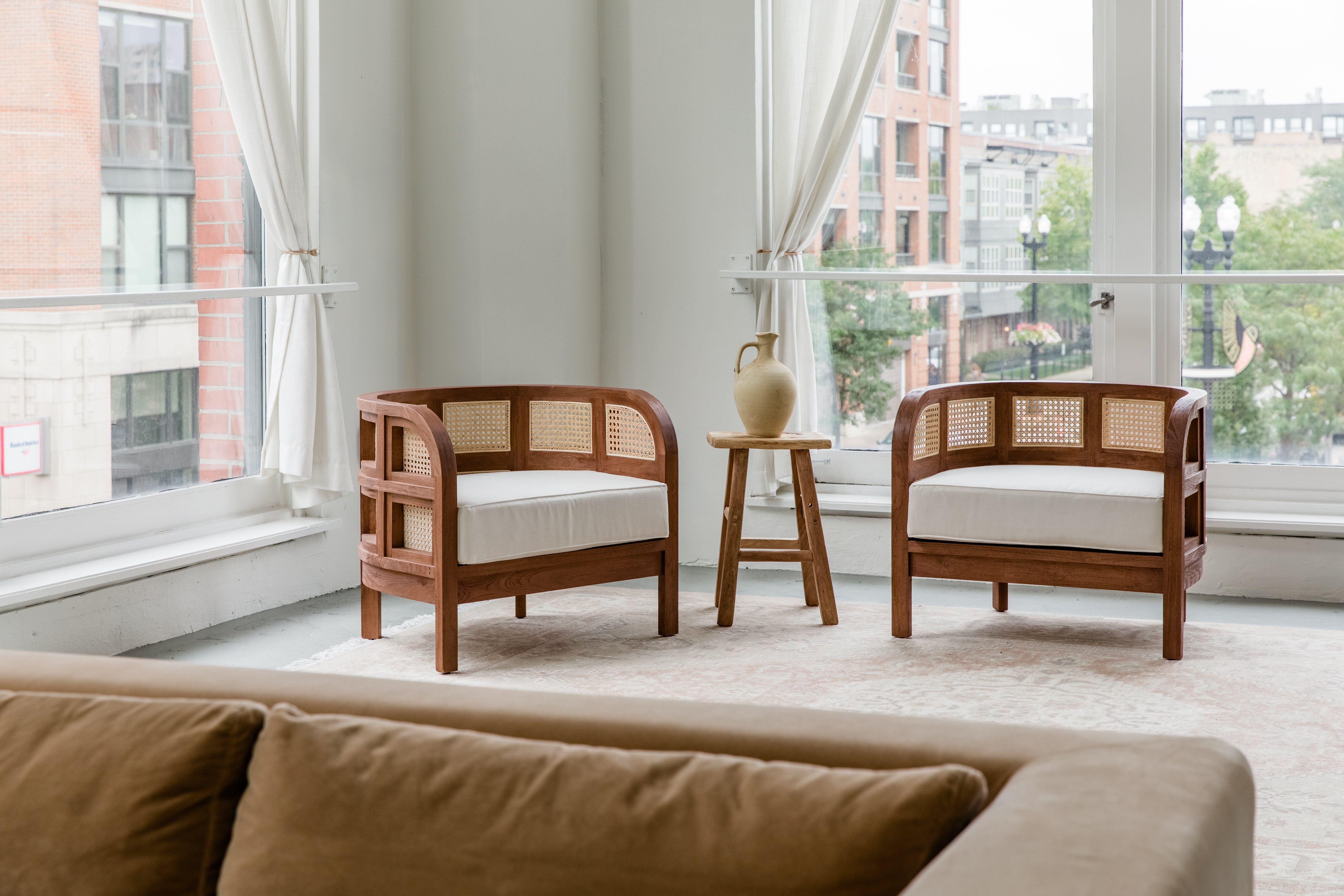 Living room scene with a pair of wooden walnut caned accent chairs with a natural sustainable vibe