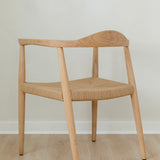 angular back view of a natural light wooden chair with a jute rope woven seat that's sustainable