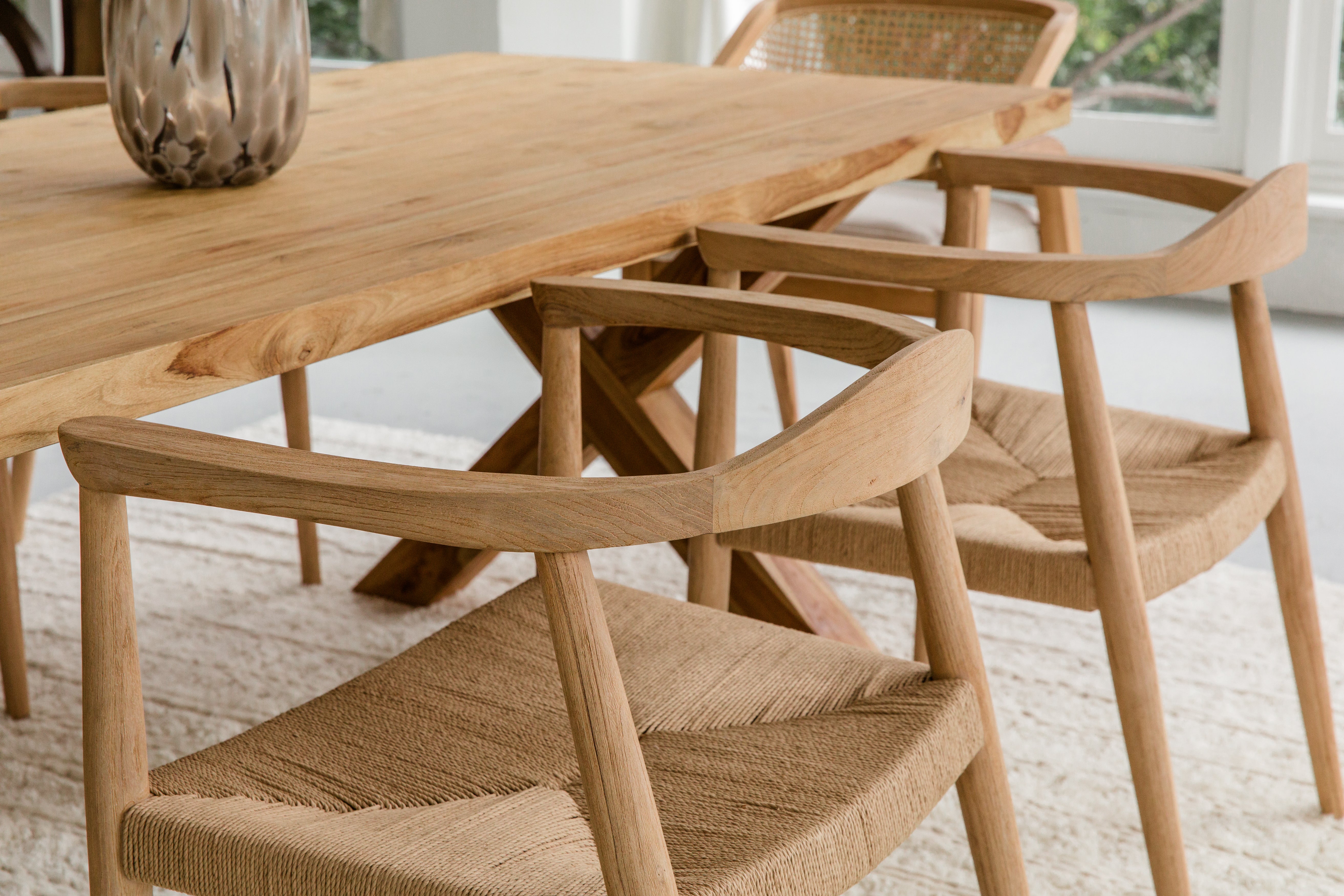 close up view of a dining room setting with natural wooden dining room tables and chairs with woven seats