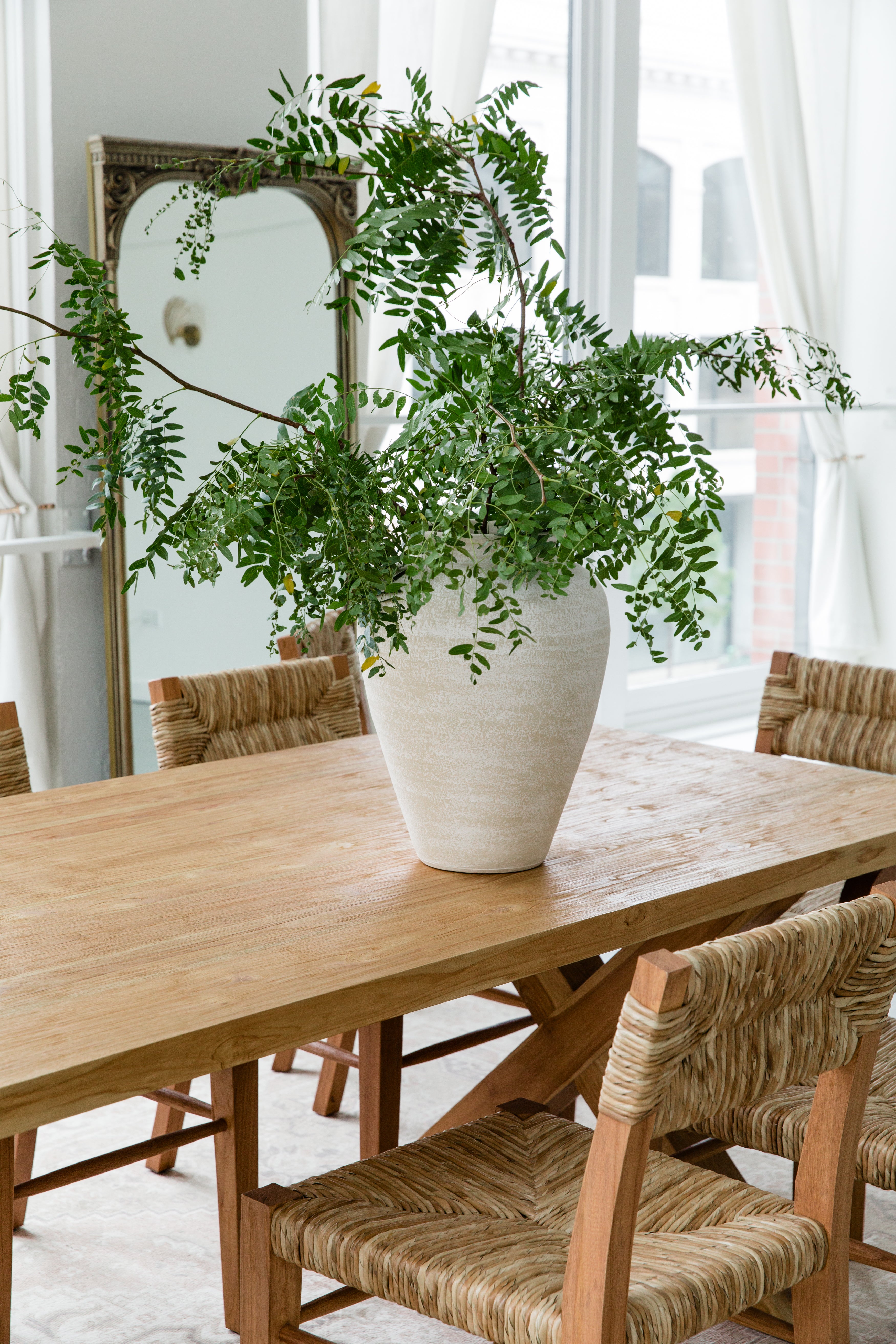 sustainable solid wood dining table and seagrass chairs in a dining room light and bright setting