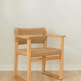 angular view of a sustainable wooden dining chair with arms and a woven jute rope seat and back