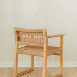 angular back view of a natural wooden dining chair with arms and a woven jute rope seat and back