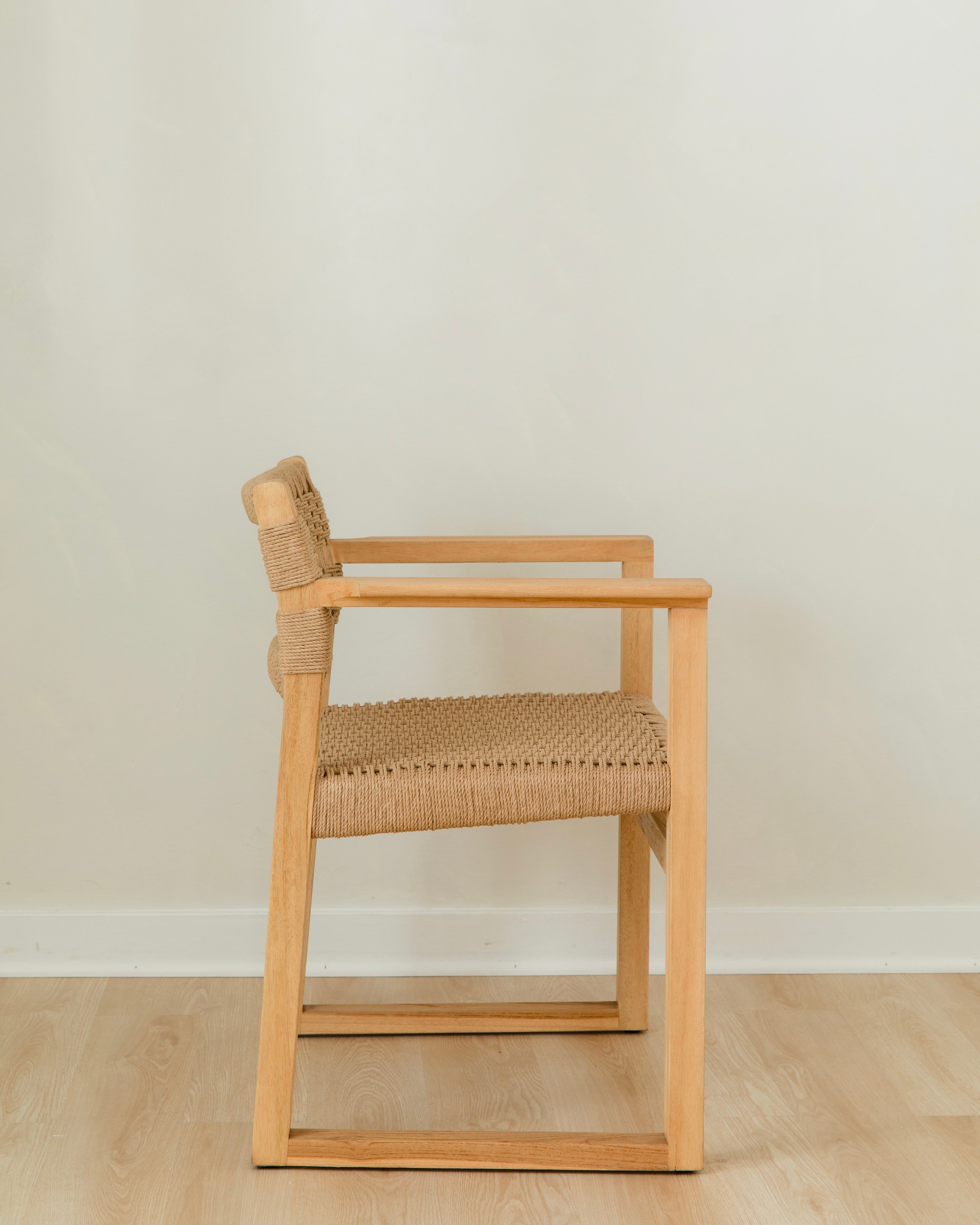 side view of a natural wooden dining chair with arms and a woven jute rope seat and back