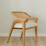 angular view of curved and caned accent chair in a natural solid teak wood with a white cushion seat