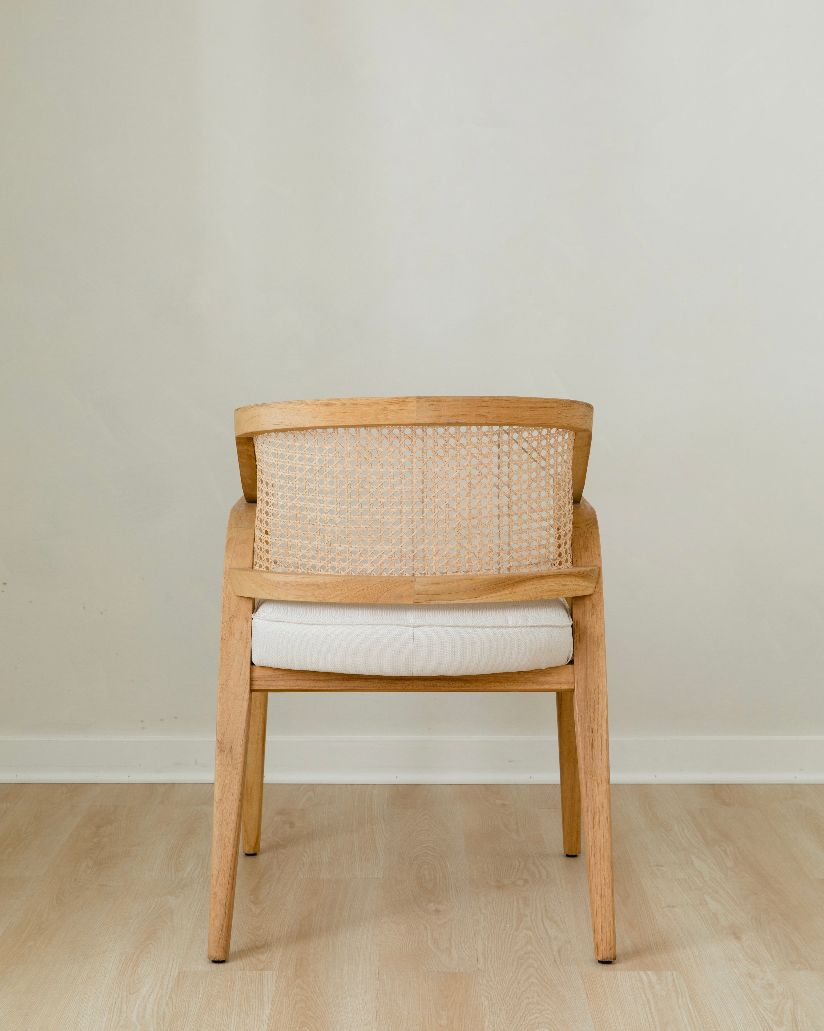 back view of curved and caned accent chair in a natural solid teak wood with a white cushion seat