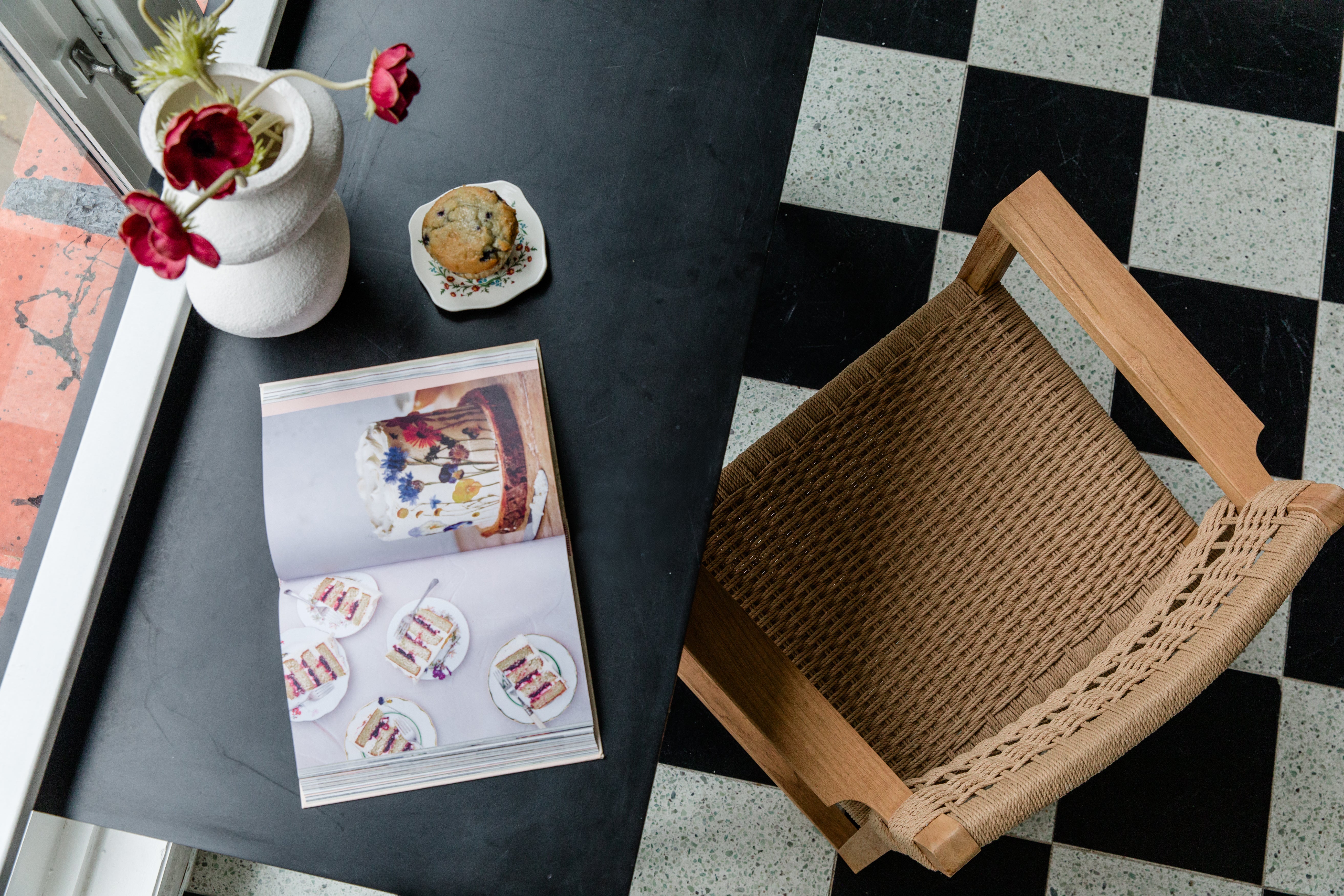 diary view of a checkerboard kitchen floor and a natural wooden and textural arm chair with flowers and decor