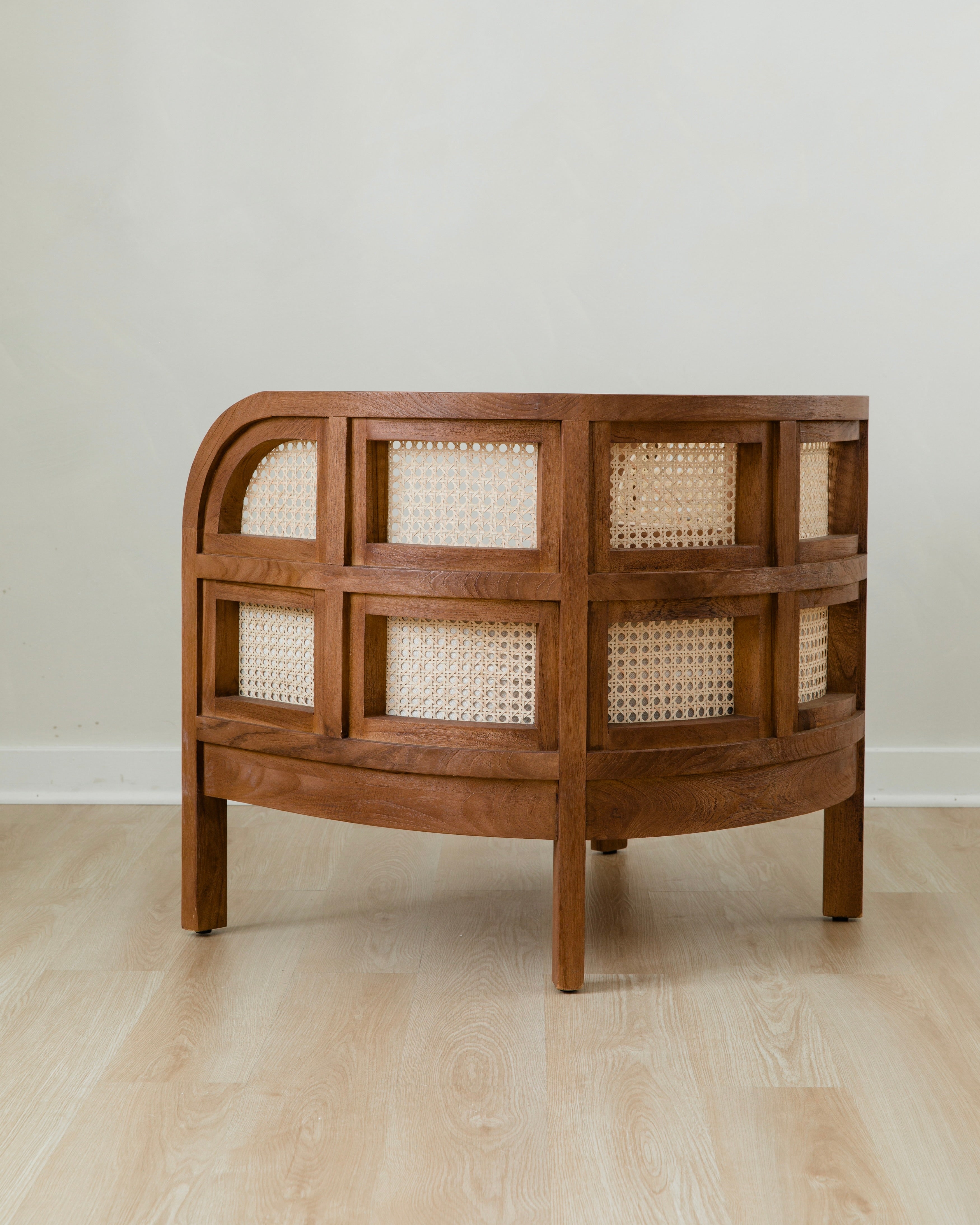 side view of curved and caned accent chair in a club style with a walnut wooden stain finish and white cushion