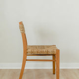 side view of a sustainable wooden chair in a honey stain with a woven seagrass back and seat