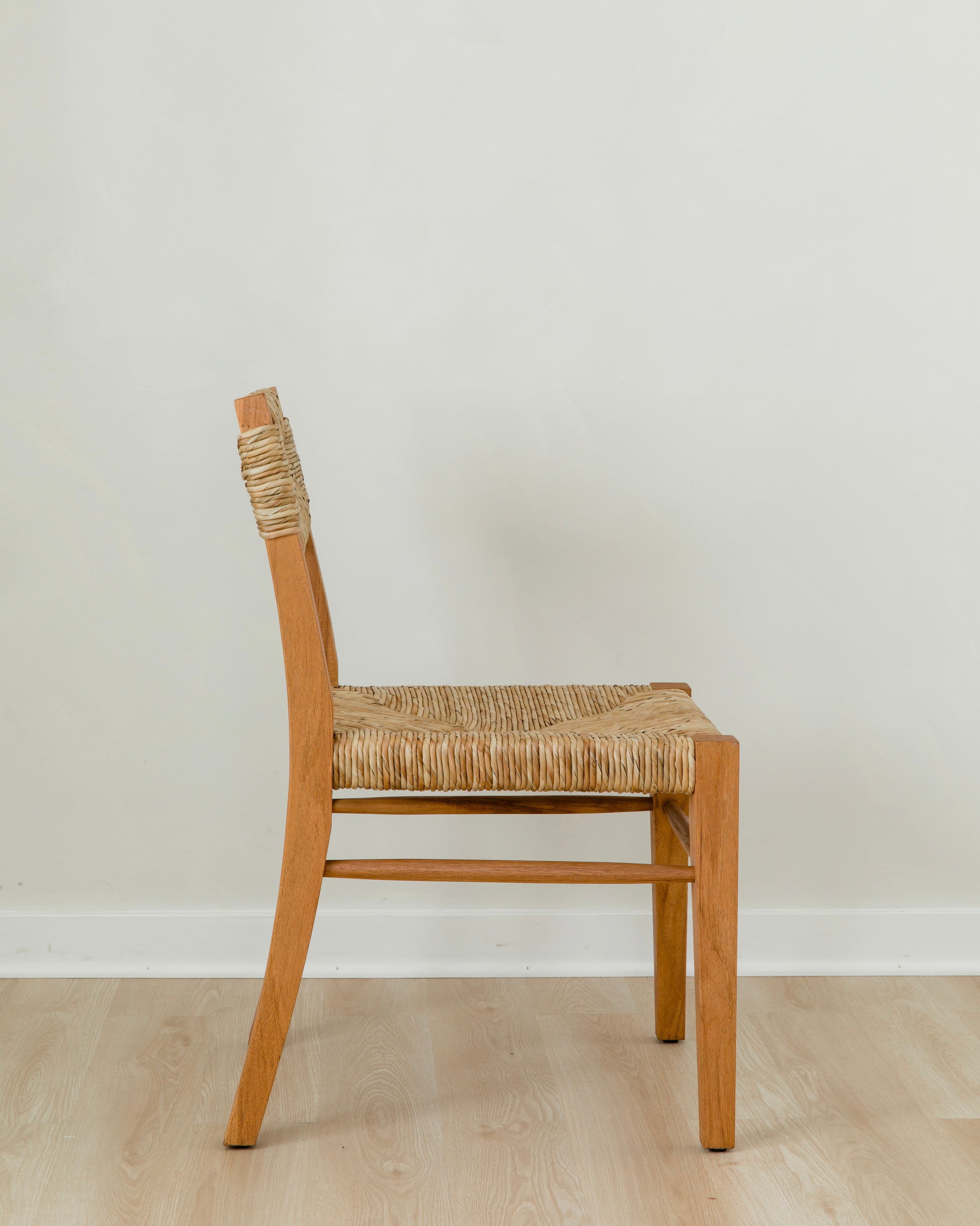 side view of a sustainable wooden chair in a honey stain with a woven seagrass back and seat