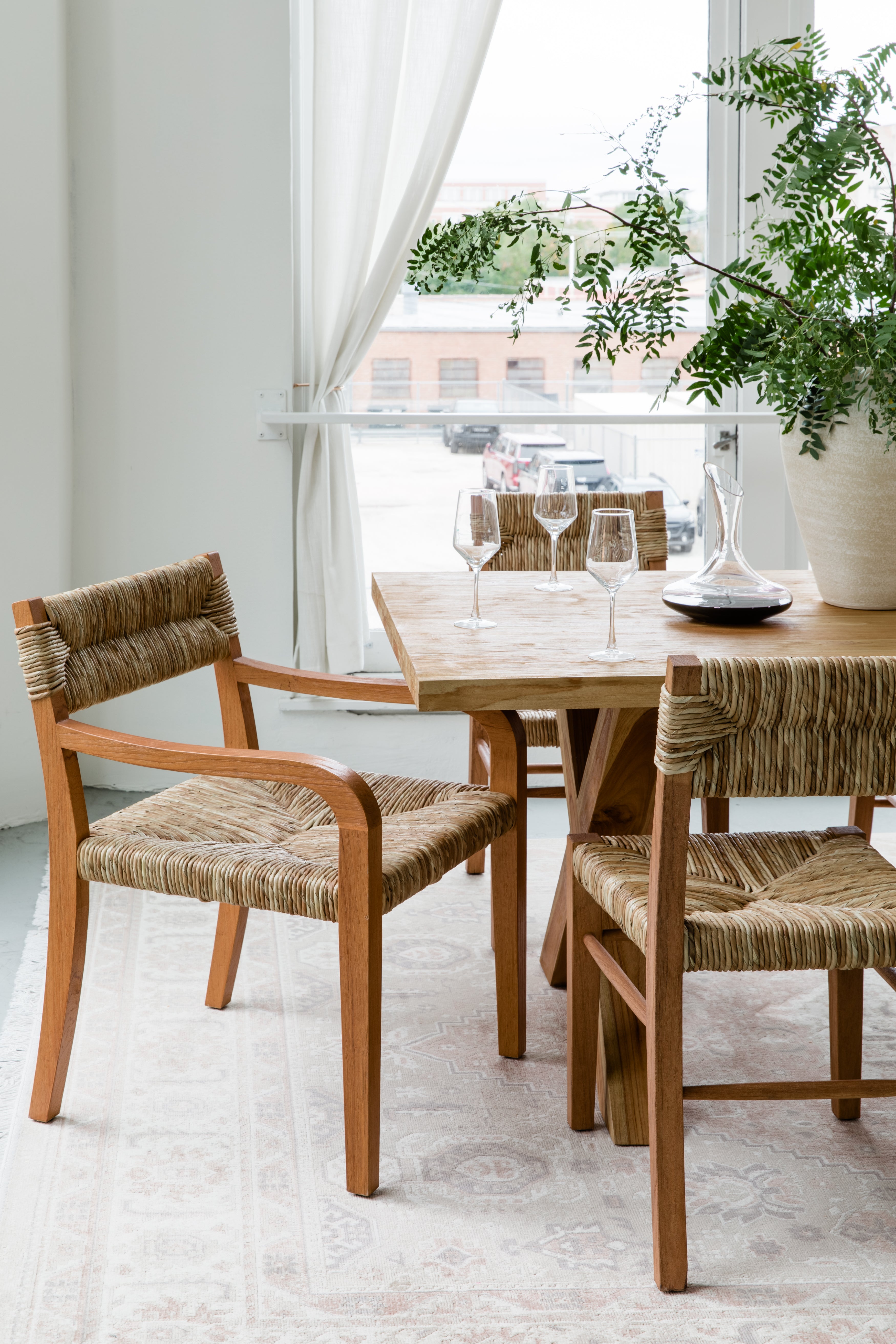 modern yet timeless dining room set up highlighting a woven seagrass dining chair with arms and a cross leg wooden dining table