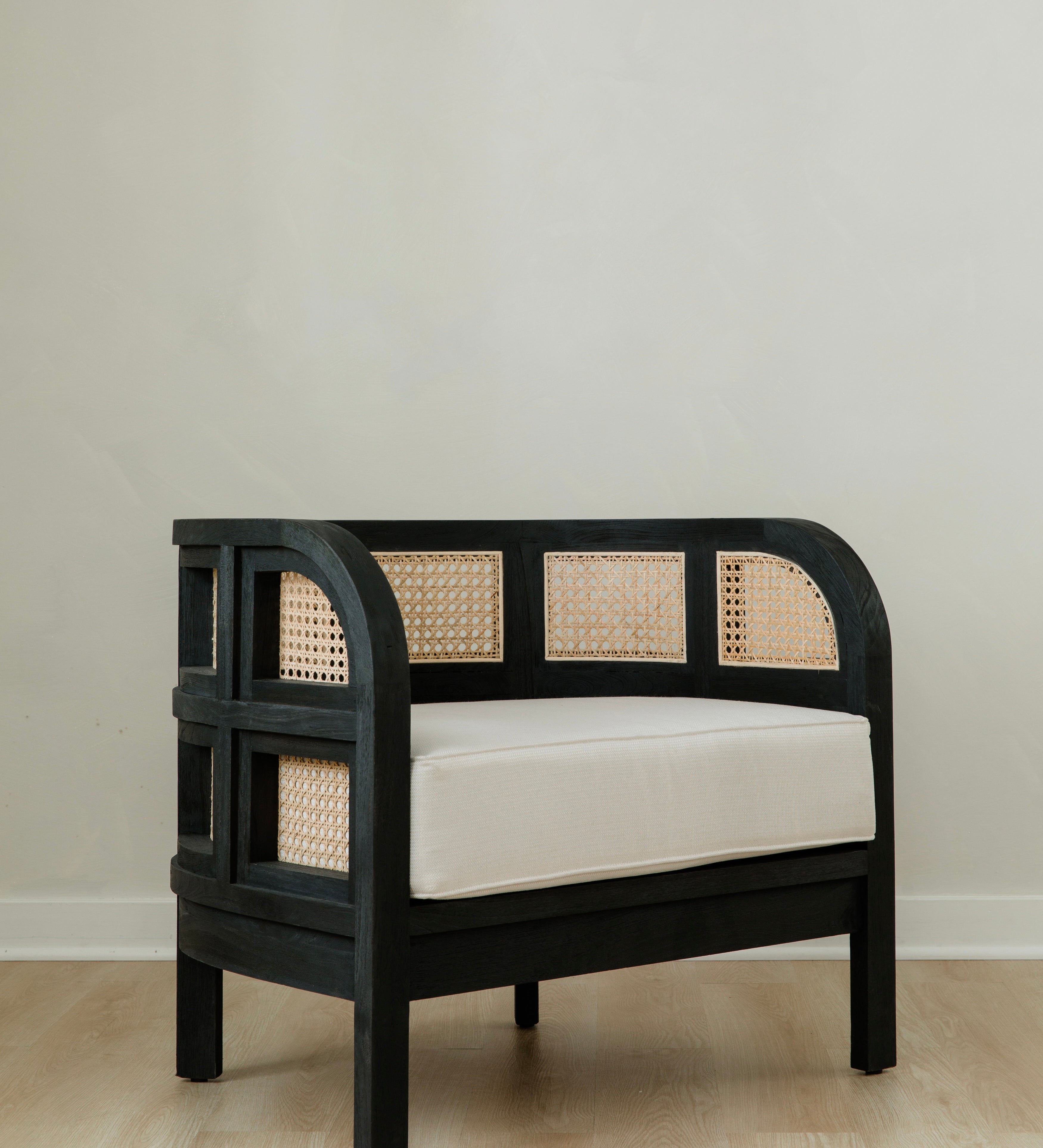 angular view of black caned and curved club chair with a white cushion seat