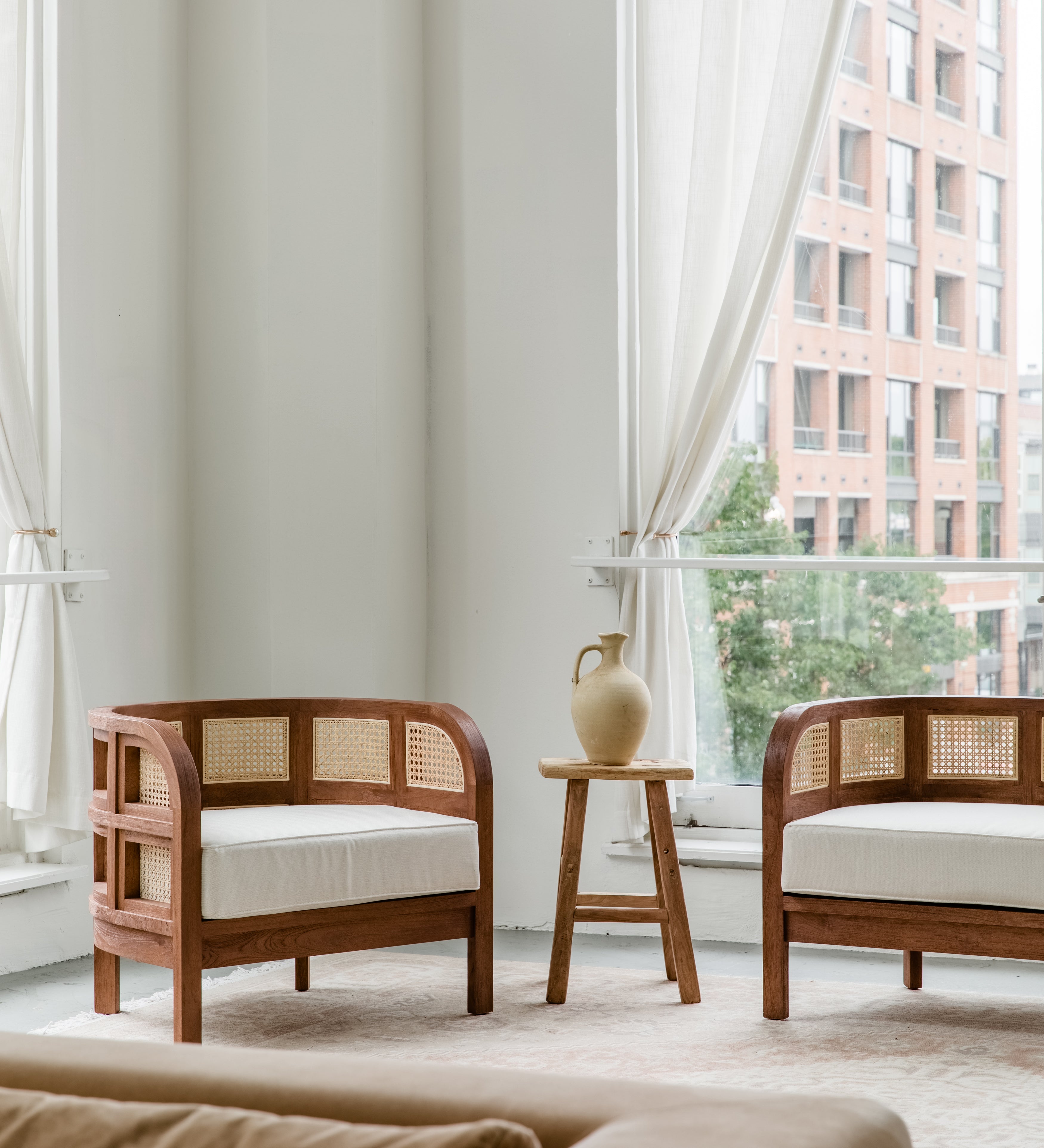 Living room scene with a pair of wooden walnut caned accent chairs with a natural vibe