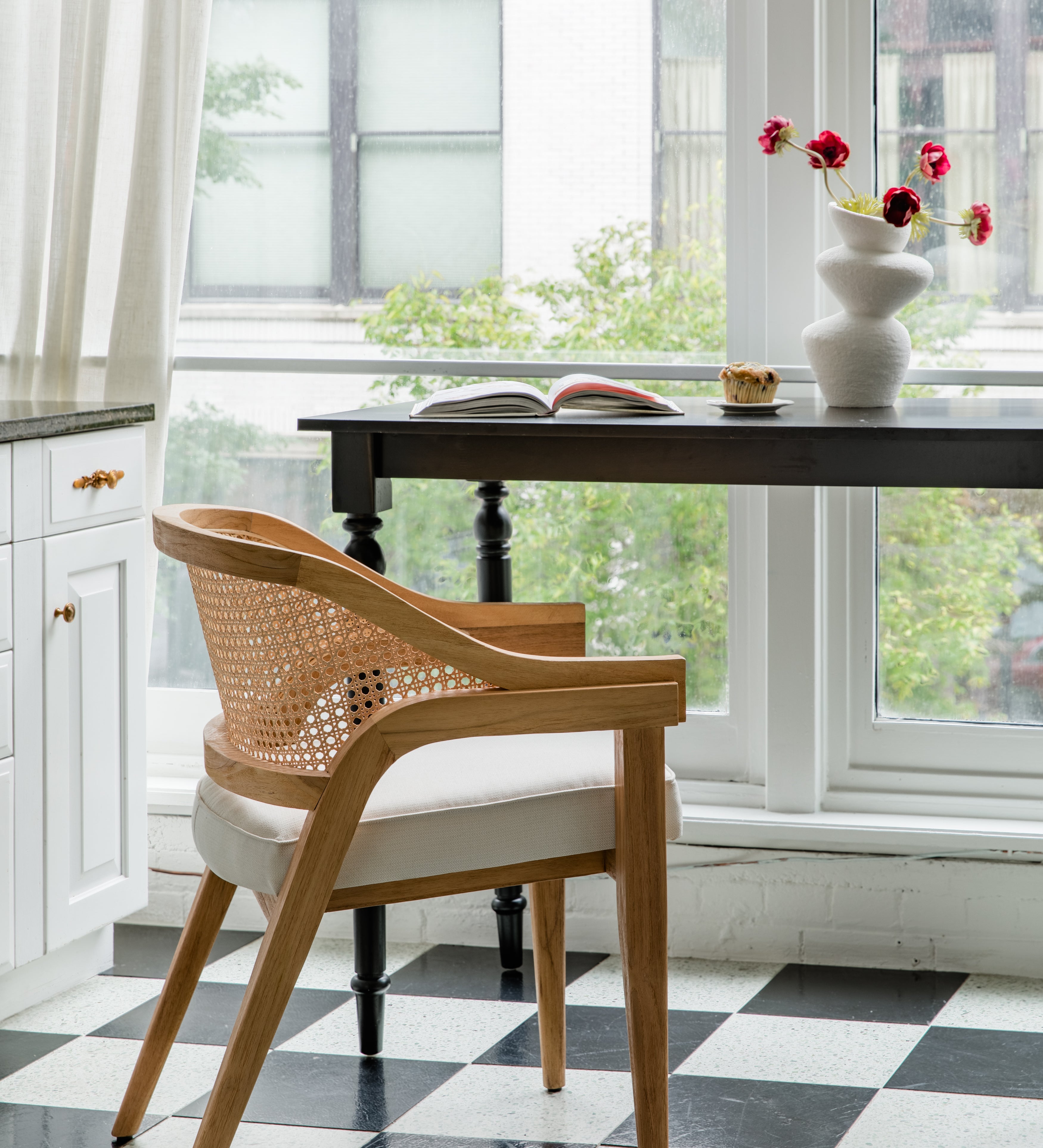 Parisian style kitchen with a checkerboard floor and a natural wooden caned curved back chair