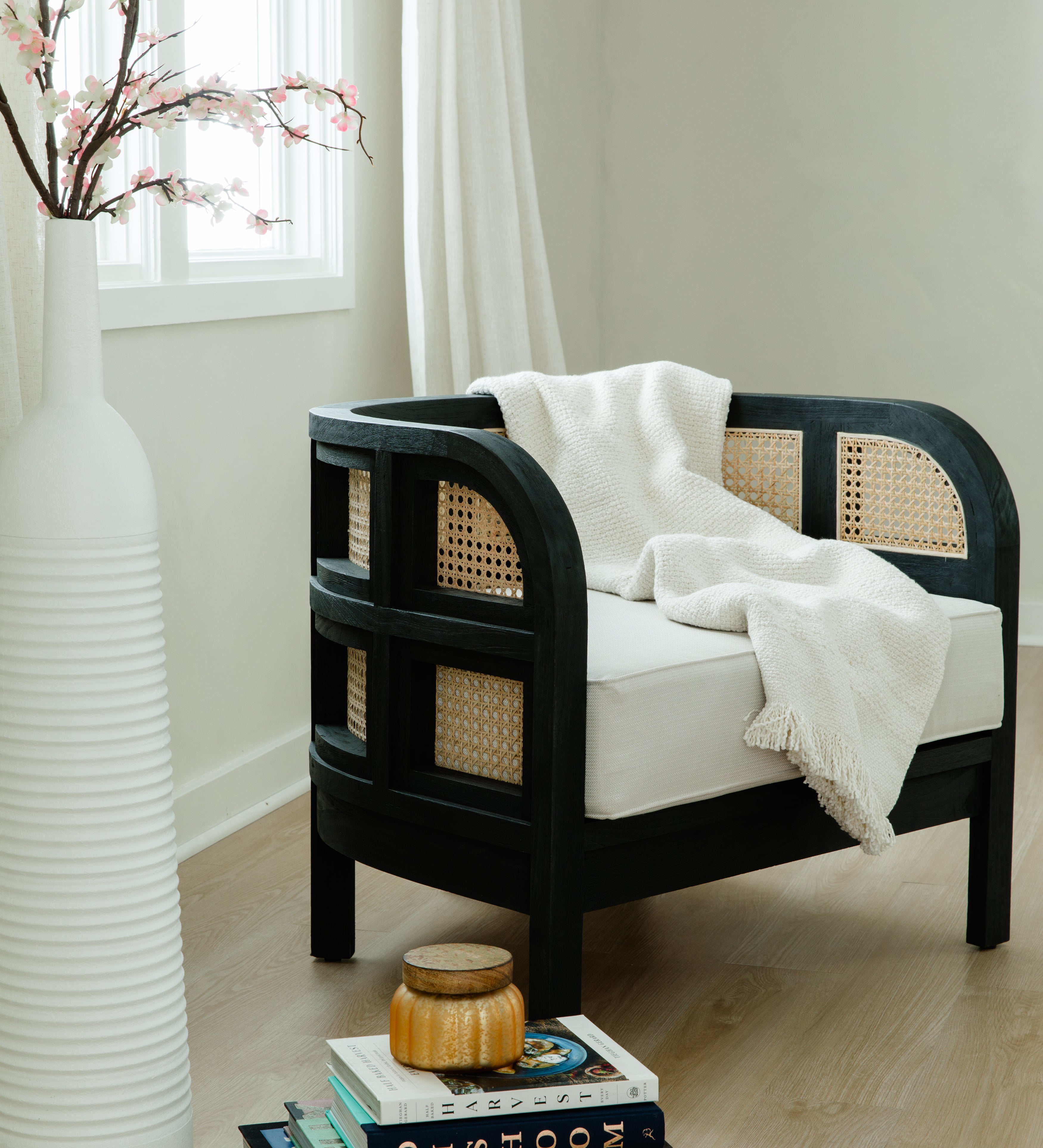 Cozy corner of a room with a black curved accent chair with a throw blanket