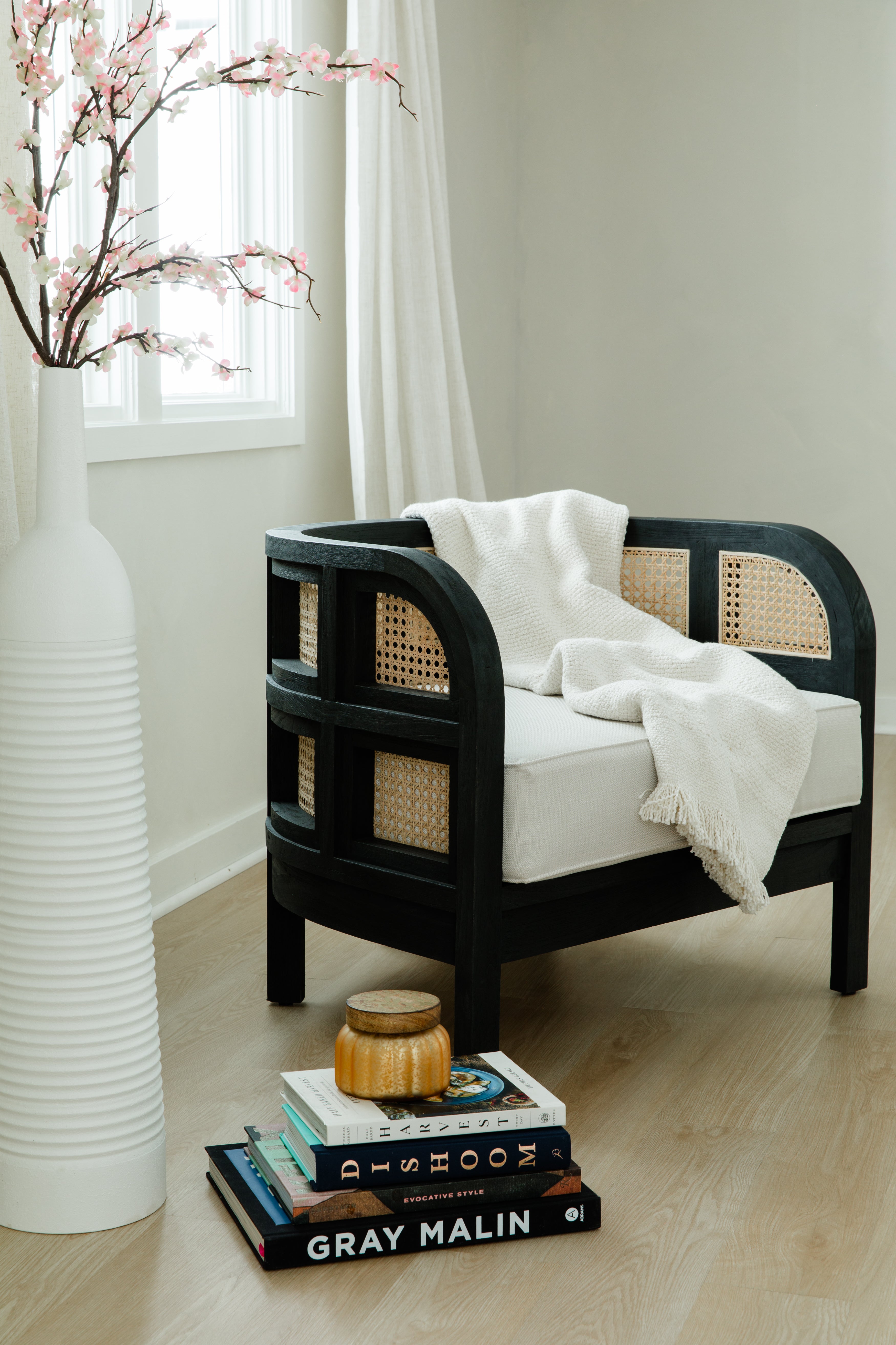 Cozy corner of a room with a black curved accent chair with a throw blanket