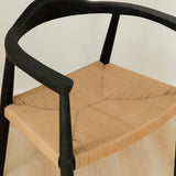 close up view of modern matte black dining room chair with a curved back and a jute rope woven seat