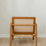 sustainable, handcrafted accent chair in rattan, with a modern, classic white cushion in a from the back view
