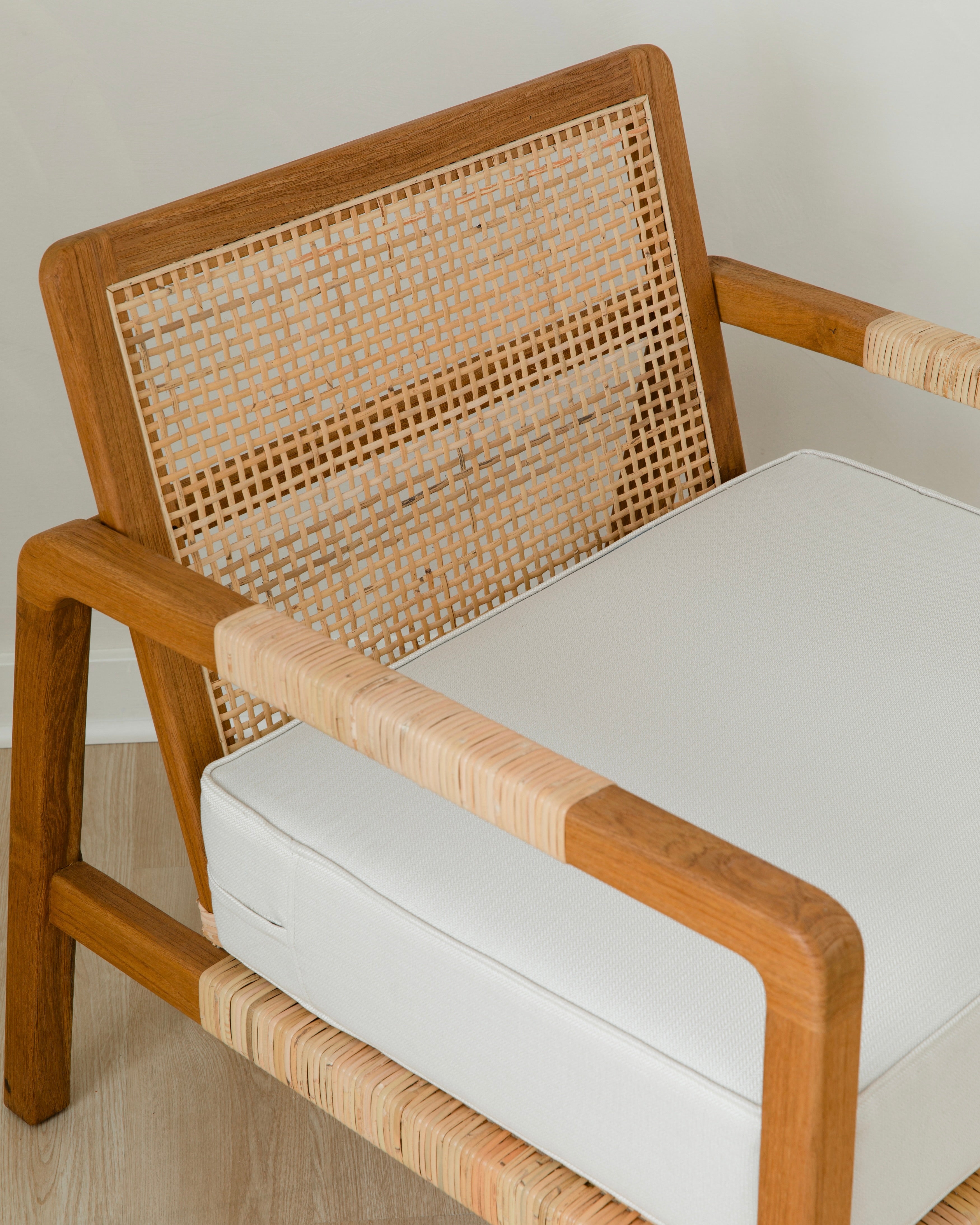 sustainable, handcrafted accent chair in rattan, with a modern, classic white cushion in a from above view