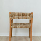 back view of a wooden dining chair with curved arms and a woven seagrass back and seat