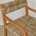 Close up view of the seagrass woven texture on a curved wooden arm dining chair