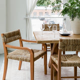 sustainable solid wood dining table and seagrass woven chairs in a dining room light and bright setting
