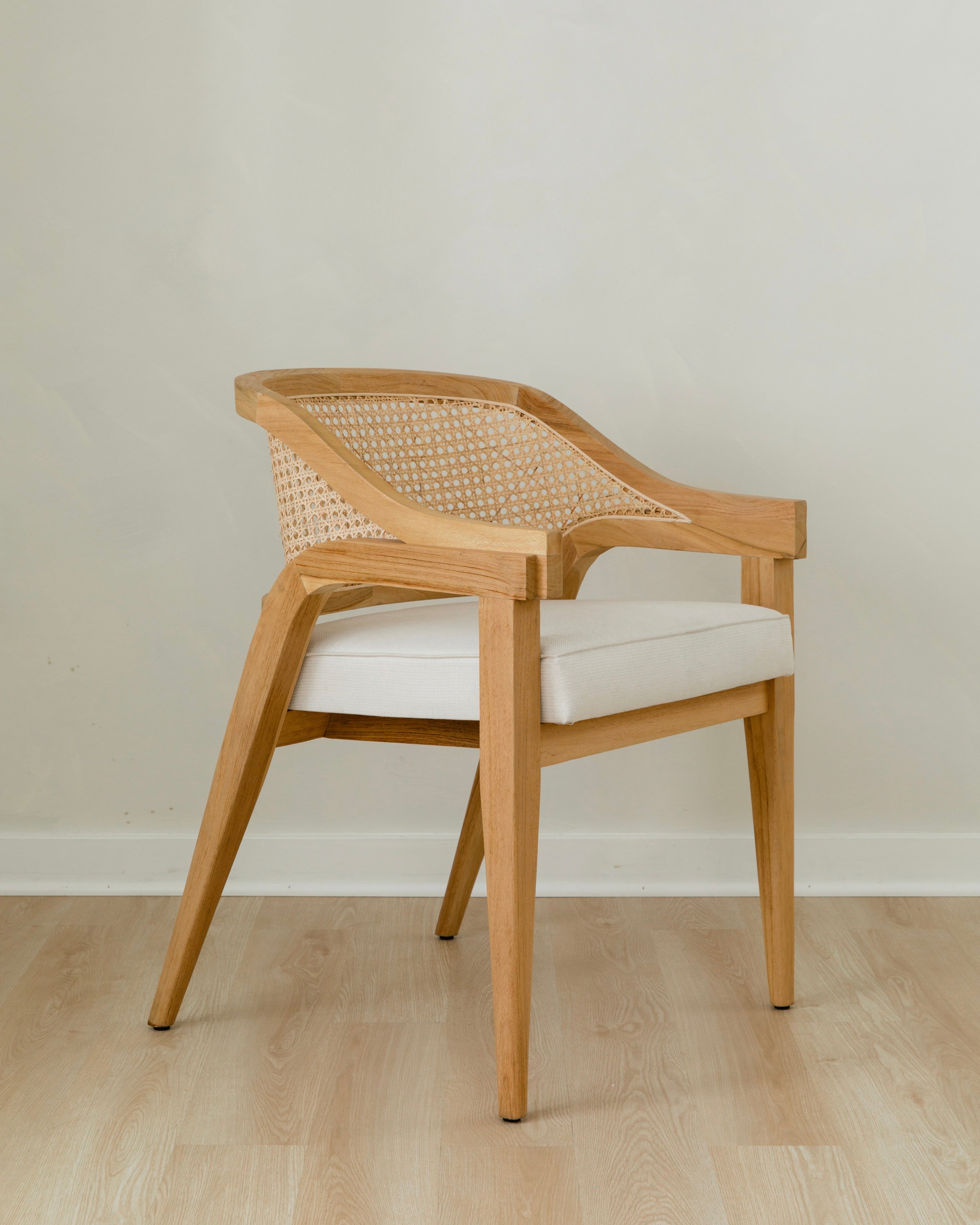 angular view of curved and caned accent chair in a natural solid teak wood with a white cushion seat