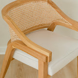 close up view of curved and caned accent chair in a natural solid teak wood with a white cushion seat