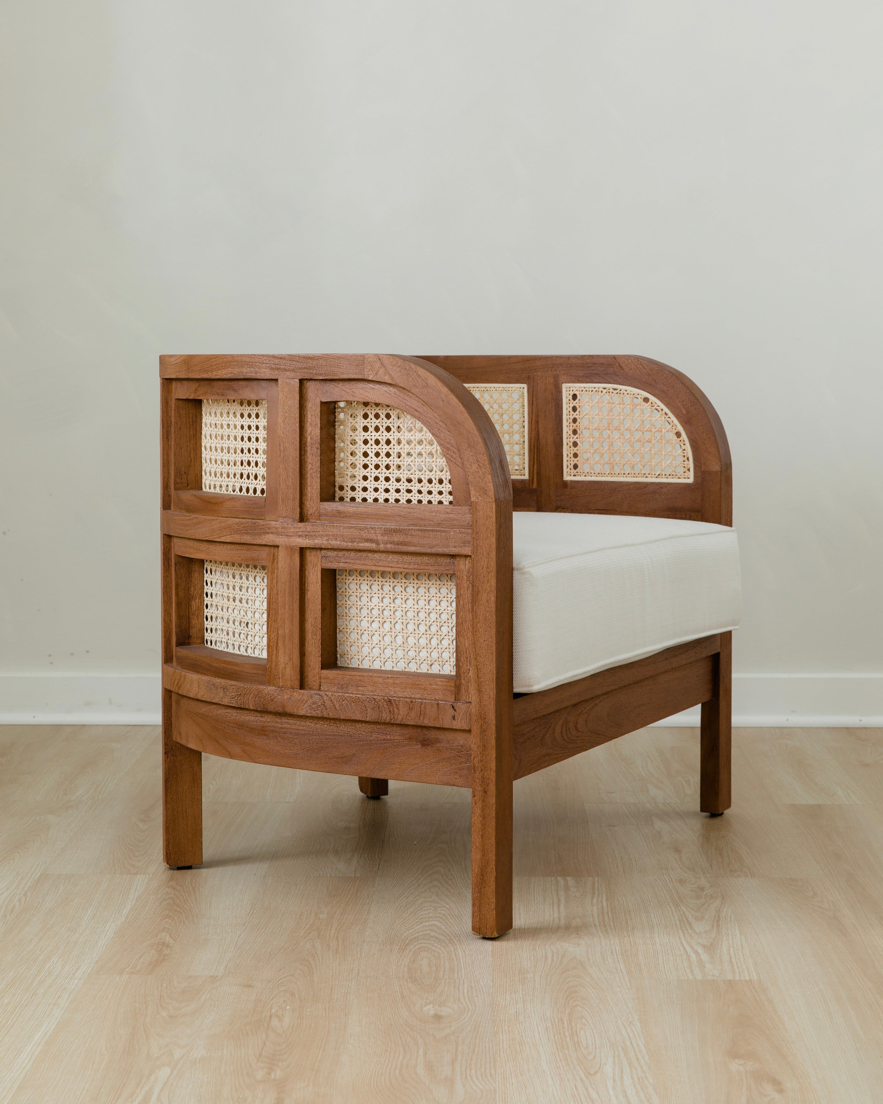 angular view of curved and caned accent chair in a club style with a walnut wooden stain finish and white cushion