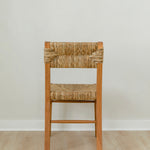 back view of a boho wooden chair in a honey stain with a woven seagrass back and seat