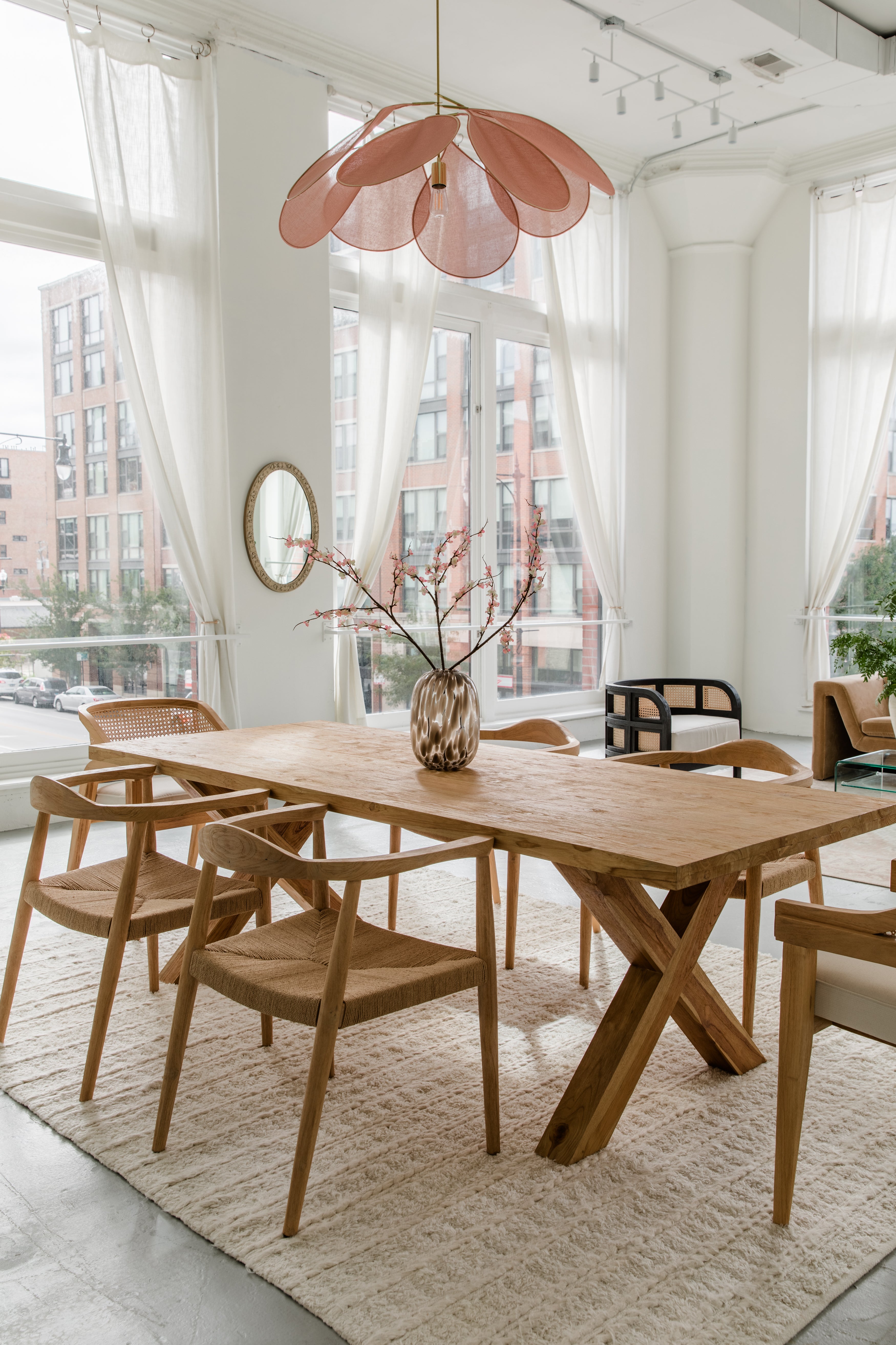 Bright city dining room with a natural wooden finish dining room table and natural wooden dining chairs with caning and jute rope detail